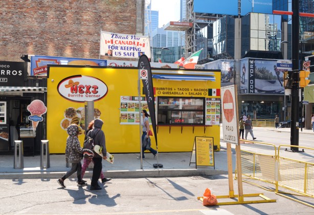 people walking on Gould Street, past a small yellow building 