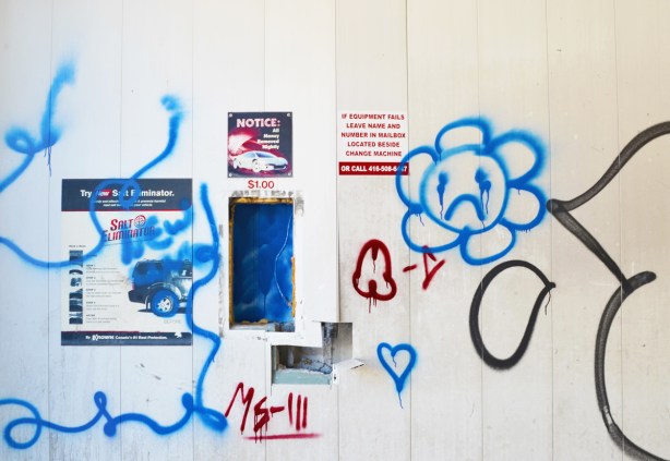 graffiti in red and blue on the interior walls of an old abandoned and emptied car wash, blue daisy frowny face