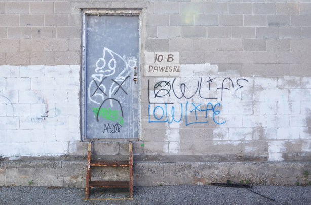 grey concrete block wall with a grey metal door, two small metal steps lead up to the door, 10 B Dawes Road on a sign 