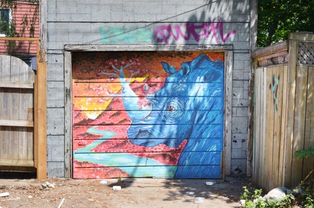 mural of rhino head and horn on a garage door in an alley, rhinoceros