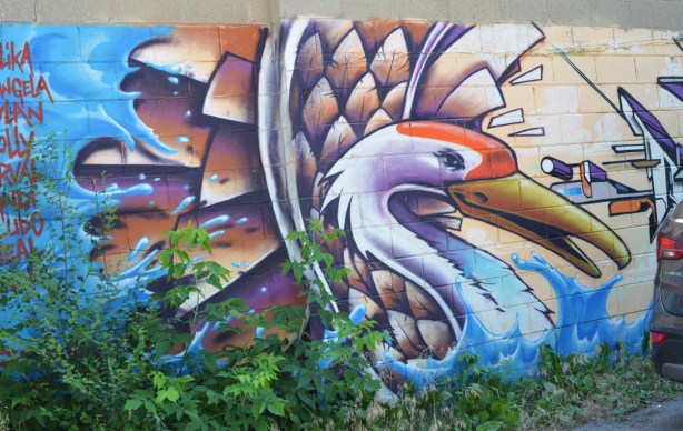 mural of a swan with a list of names to the left and a piece by mediah to the right 