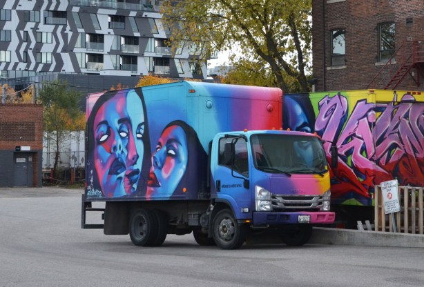 Henderson Brewery delivery truck covered with street art by kizmet, 3 faces in shades of blue, purple, pink, and turquoise 