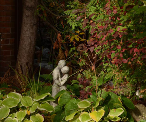small statue of a couple embracing in a garden in a front yard 