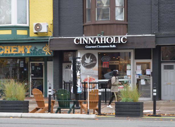 a woman walks past Cinnaholic, a store selling gourmet cinnamon rolls