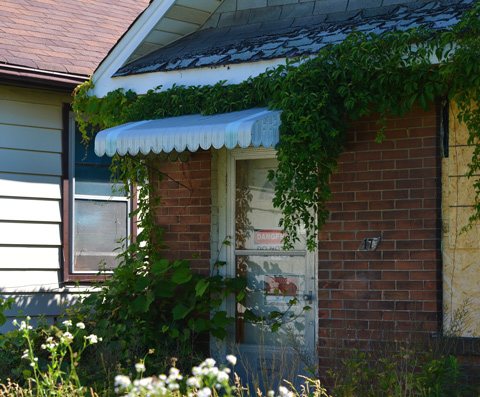 empty boarded up house with danger sign onthe front door