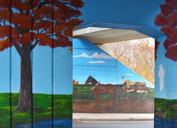 a man on a horse drawn carriage making deliveries, part of a mural