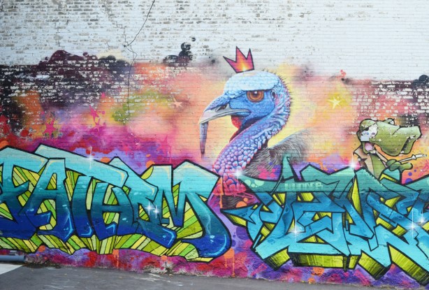 a mural, turkey head, wearing red three pointed crown, with wildstyle graffiti across the bottom 