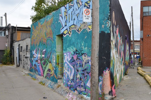 the point of a wedge shaped building with street art on both sides 