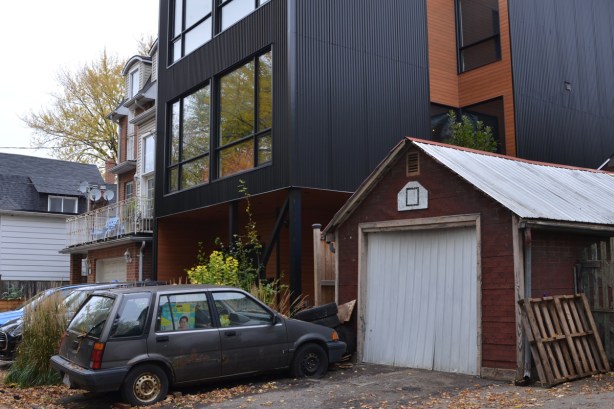 old car and old garage in front of a large new modern house