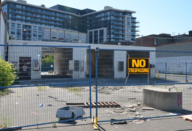 no trespassing sign on a fence around an old abandoned car wash 