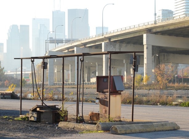 old gas pump at now abandoned marine gas station beside the Keating channel, Gardiner Expressway, CN Tower and Toronto skyline in the distance