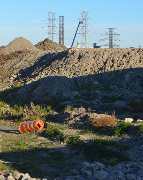 hydro poles and wires in the distance, piles of dirt in the foreground 