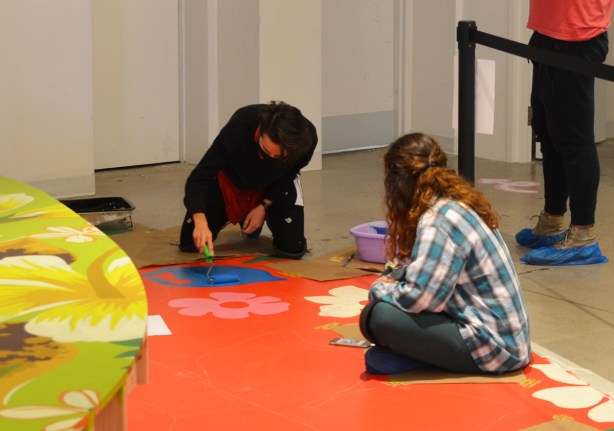 women painting on the floor of a gallery