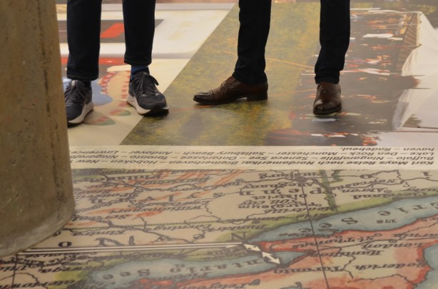 calves and shoes of people standing on pictures on the floor of a gallery