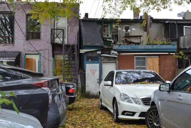 used cars parked behind two empty buildings 
