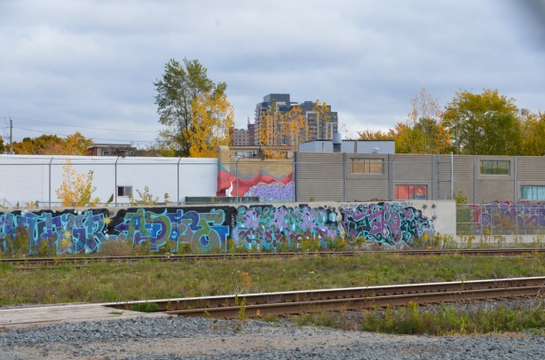 a wall of street art on the other side of the railway tracks 
