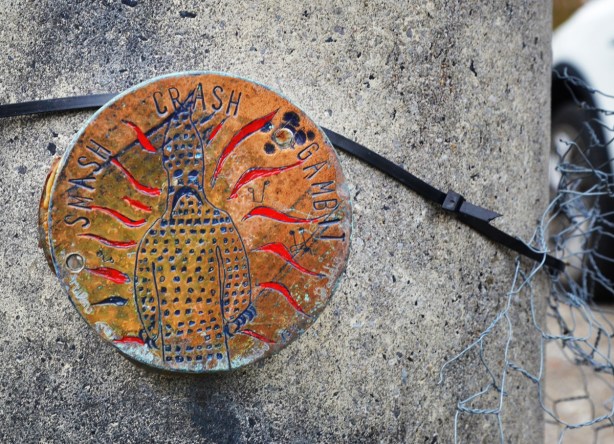 small round medallion shaped graffiti, carved figure with words crash smash gambit written around the outside 