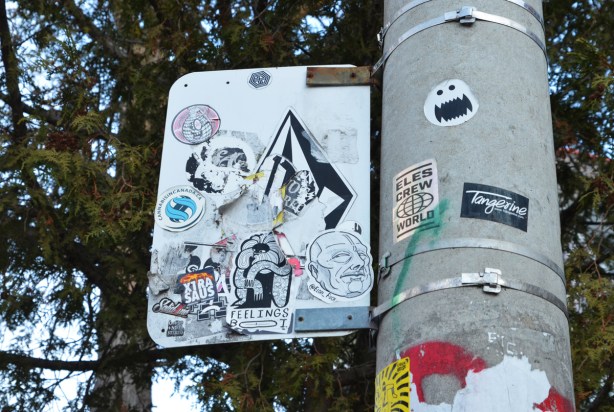 graffiti stickers on the back of a street sign 