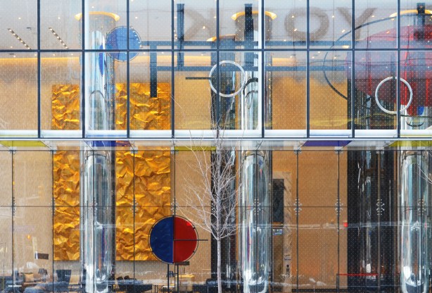 looking into the lobby of a condo building, through a large glass wall, some art inside including a large wall panel that looks like crinkled shiney gold paper, some reflections, 