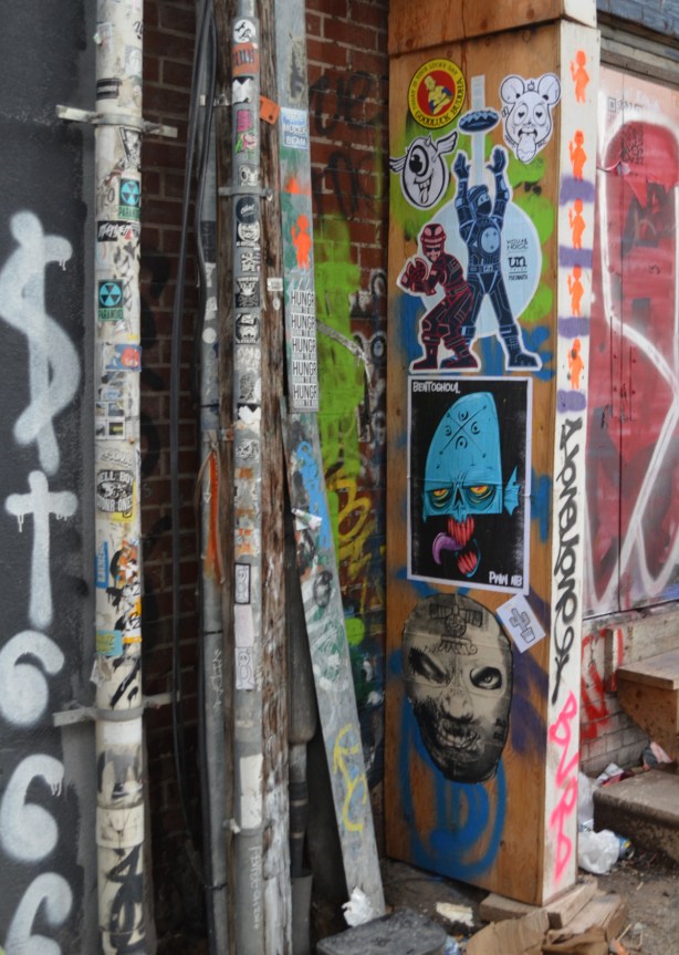 pasteups and stickers on a wall in graffiti alley 