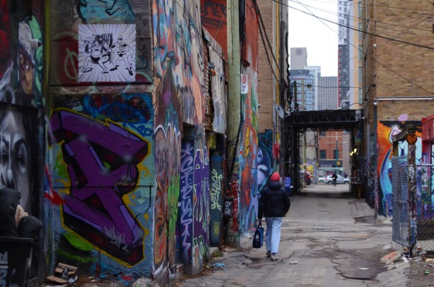 a man walks down graffiti alley