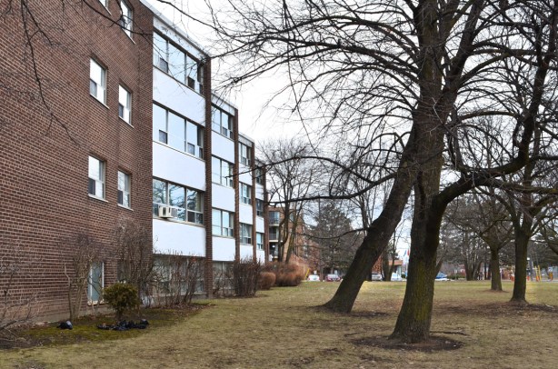 low rise apartment building with trees and grassy space beside it