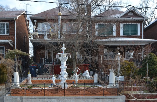 two adjacent two storey houses with lots of white statues and fountains in the front yards