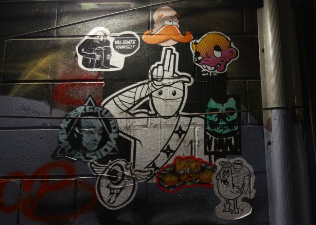 stickers and paste ups on a wall in graffiti alley 