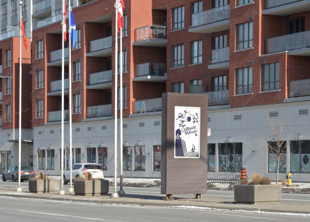in the median, Kingston Road, a sign that says Cliffside Village, red brick apartment building behind 