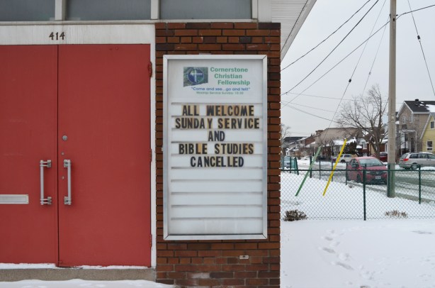 sign beside the red doors of Crossroads Christian fellowship church that says All welcome Sunday service and bible studies cancelled 