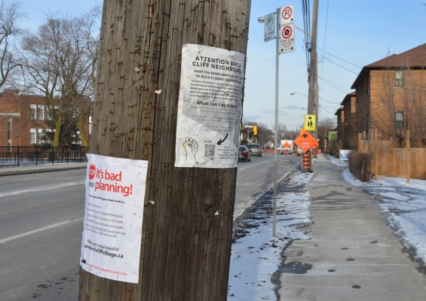 two posters on a wood utility pole, protesting redevelopments in the neighbourhood