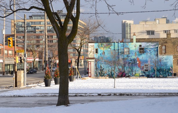 picture of a mural as seen from across a park, street scene as well. snow, winter, 