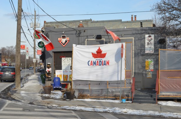 Molson Canadian flag outside a bar, also muskoka chairs and a carved wood bear, a Canadian flag too. 