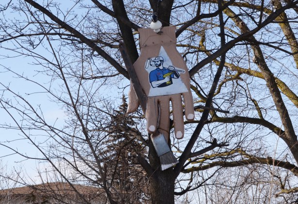 an advertisement for a handyman, a large hand up in a tree with a paintbrush 