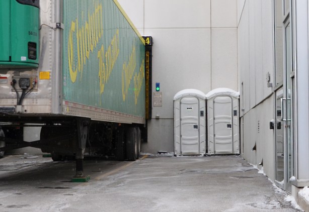two white port a potties beside a parked truck container back part 