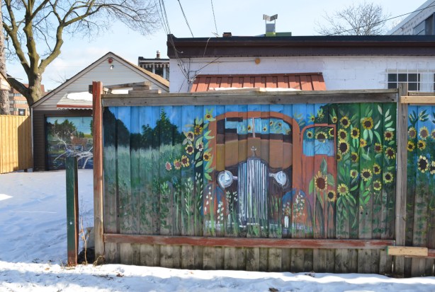 B C Johnson mural of an old car surrounded by sunflowers in an alley