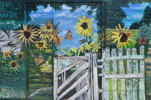 sunflowers and butterflies on a summer day, and a gate made of birch branches, a mural in an alley by Bc johnson