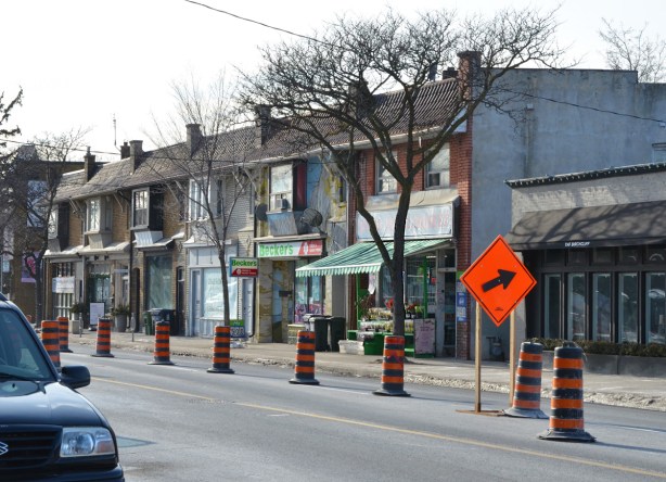row of two storey brick storefronts including a Beckers store with a birch tree mural on it 