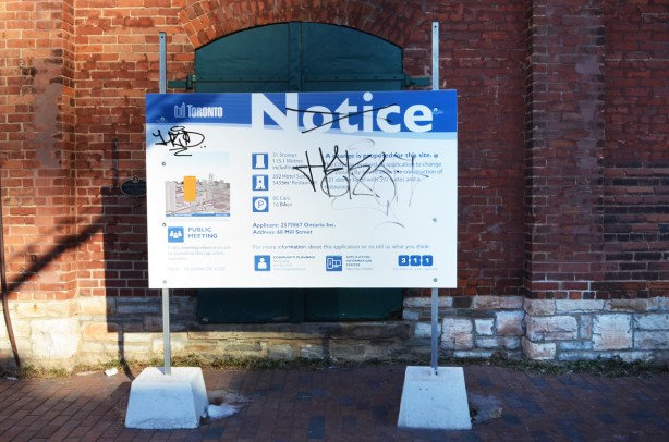 blue and white city of toronto development notice in front of old brick building in distillery district