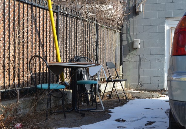 table and chairs behind a building in an alley 