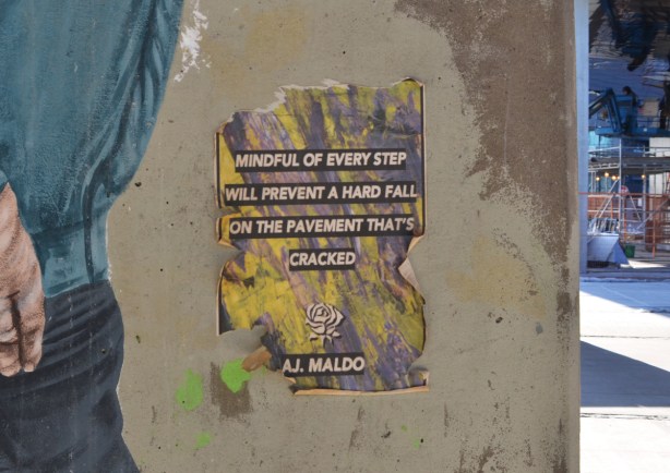 poster graffiti on a piller in Underpass Park, poetry on it