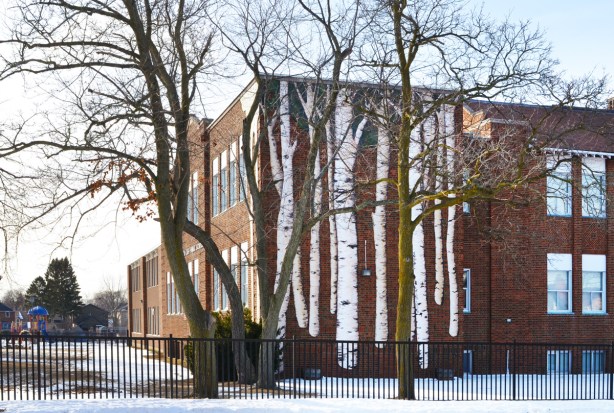 Birch cliff public school, a two storey red brick building, with a large mural of birch trees on one exterior wall 