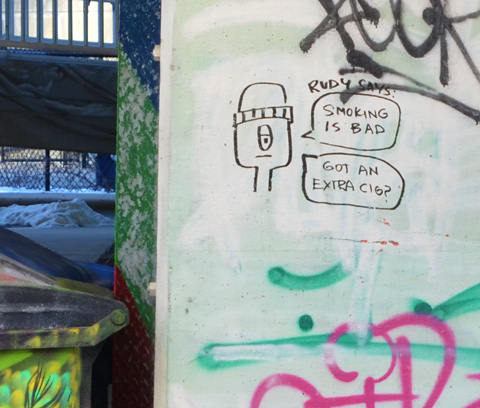 black marker scrawl graffiti on a concrete post, drawing of man's face and head with words about smoking