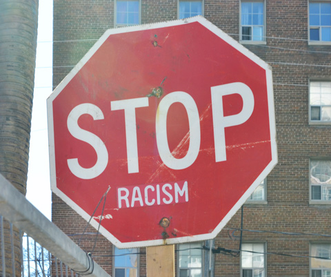 red octagonal stop sign that now says stop racism 
