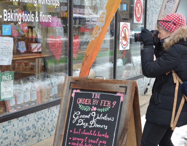photographer taking a picture of a store window, masks, baking things, red hearts, 