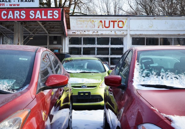 cars parked outside in the snow at a used car lot 