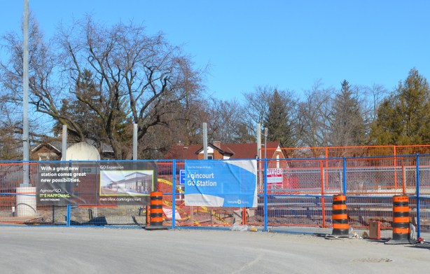 signs on construction fence at Agincourt GO station showing picture of new station