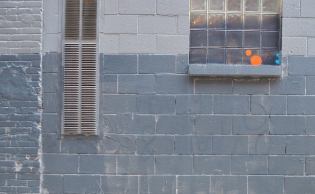 a grey wall with a window, some coloured circles painted on the window 