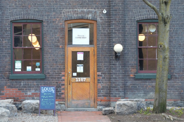 exterior of Coffee Shop Loiue with sign in window above door that says this is a coffee shop