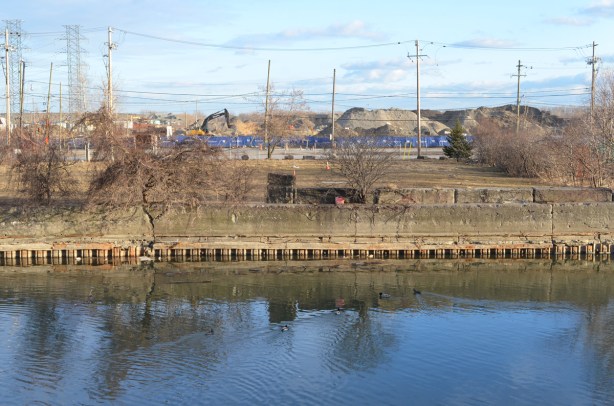 construction in the background, blue digger, vacant land, and the Keating channel in the foreground, ducks in the water